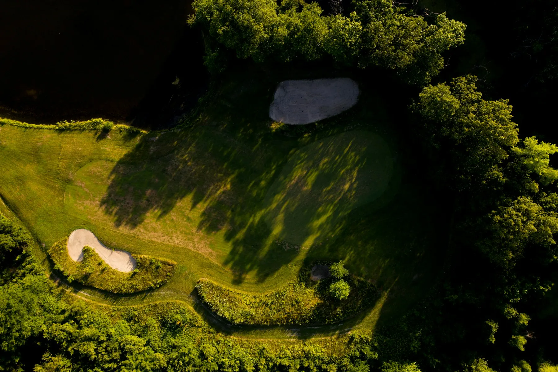Aerial view of a golf fairway surrounded by trees and sand bunkers